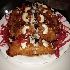 A picture of Flattened rice pitha in jaggery sauce with kheer stuffing.