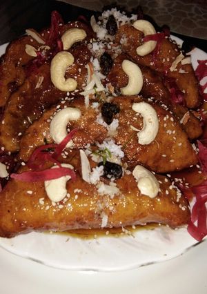 A picture of Flattened rice pitha in jaggery sauce with kheer stuffing.