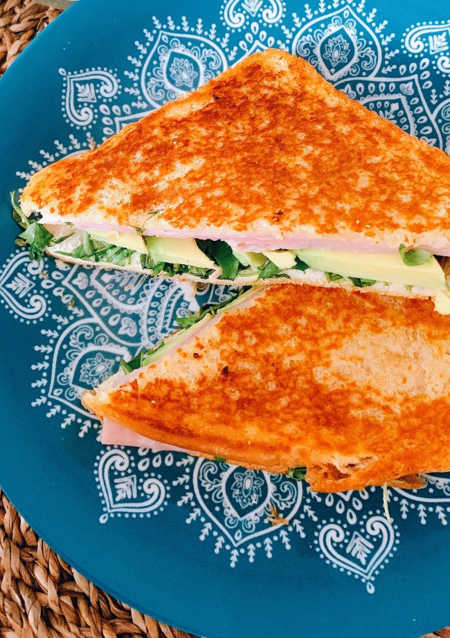 Una foto de Sándwich doradito de york, aguacate y rúcula