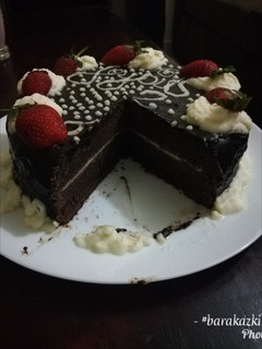 A picture of Chocolate cake with chocolate ganache and whipped cream icing.