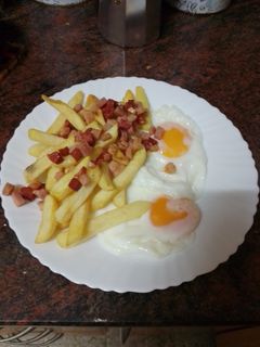Una foto de Huevos fritos con papas fritas y picada de chorizo y bacon