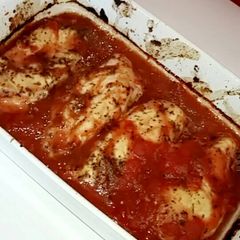 A picture of Chicken breast in a tomato and herb sauce.