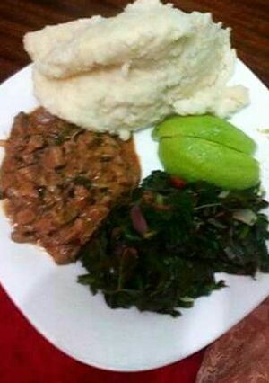 A picture of Ugali, spinach, avocado with wet fried beef.