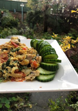 A picture of Scrambled eggs, parsley and tomatoes.