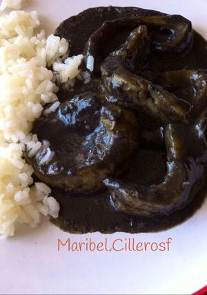 Una foto de Anillas de calamar en su tinta, con guarnición de arroz blanco