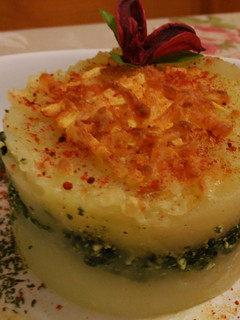 Una foto de Pastel de patatas con espinacas y ricota, bajo esquirlas de parmesano
