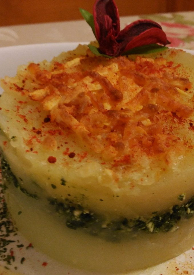 Una foto de Pastel de patatas con espinacas y ricota, bajo esquirlas de parmesano