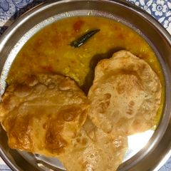 A picture of Poori with pasi paruppu sambar.