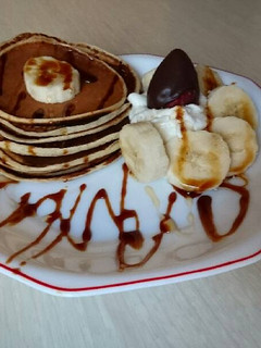 Una foto de Pancakes con nata, plátano, miel y sirope