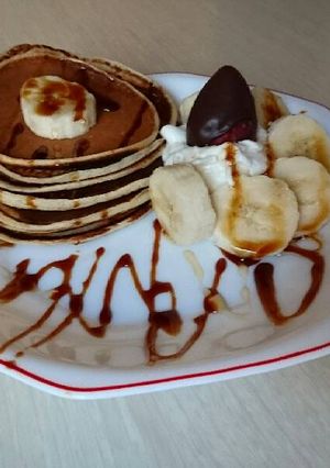 Una foto de Pancakes con nata, plátano, miel y sirope