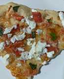 Pizza casera de tomate, queso de cabra y albahaca fresca