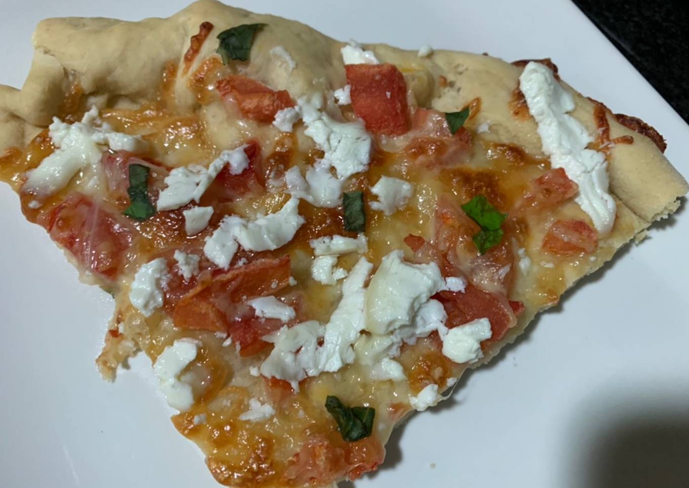 Pizza casera de tomate, queso de cabra y albahaca fresca