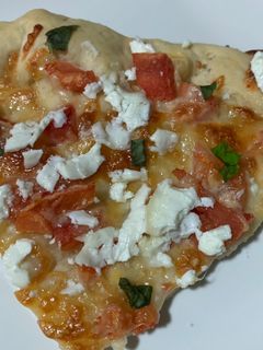 Una foto de Pizza casera de tomate, queso de cabra y albahaca fresca
