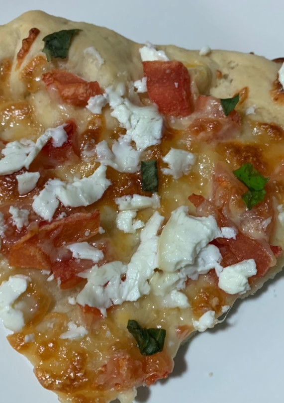 Una foto de Pizza casera de tomate, queso de cabra y albahaca fresca