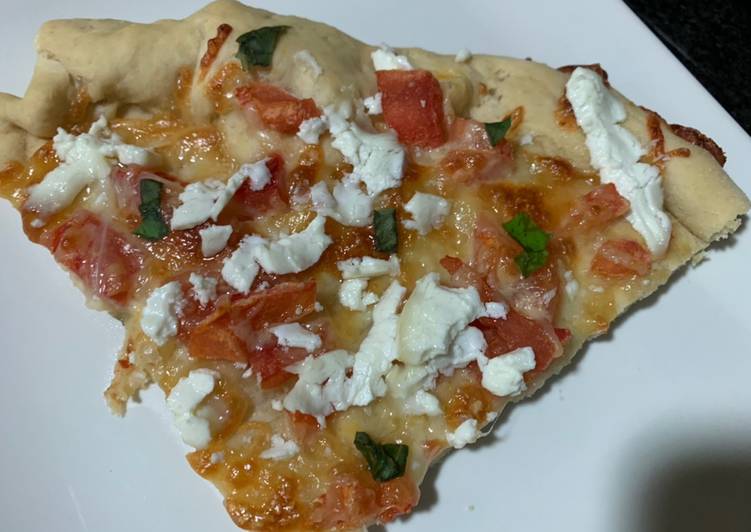 Pizza casera de tomate, queso de cabra y albahaca fresca