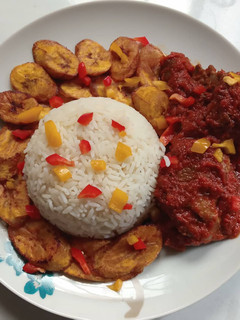 A picture of Rice, fried plantain and stew.