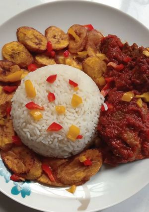A picture of Rice, fried plantain and stew.