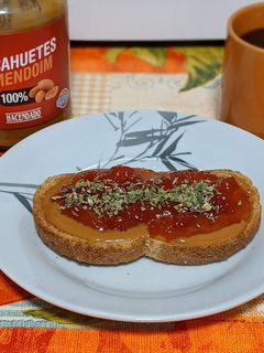 Una foto de Tostada integral con crema de cacahuete, mermelada de tomate y orégano