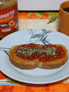 Una foto de Tostada integral con crema de cacahuete, mermelada de tomate y orégano