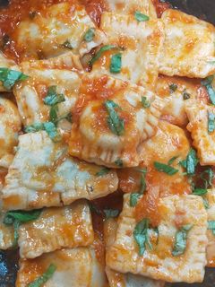 Una foto de Raviolis rellenos de espinacas y ricota con salsa de tomate y albahaca