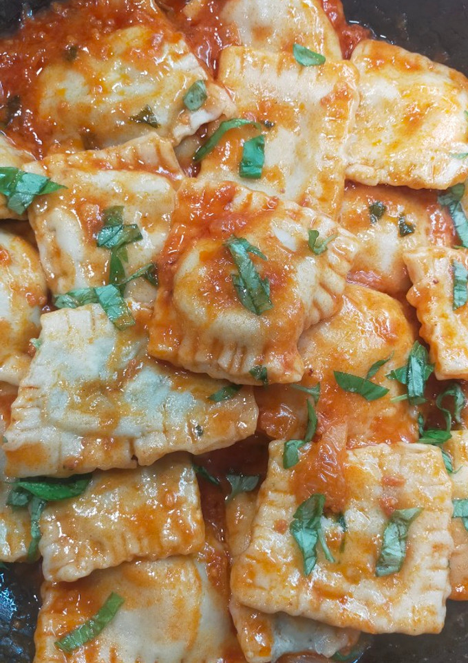 Una foto de Raviolis rellenos de espinacas y ricota con salsa de tomate y albahaca