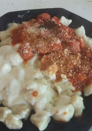 Una foto de Ñoquis de papa con salsa roja y blanca