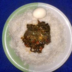 A picture of White rice and boiled egg with vegetable sauce.