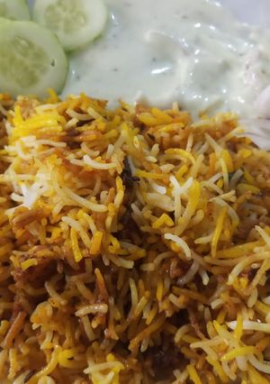 A picture of Chicken briyani with raita and salad.