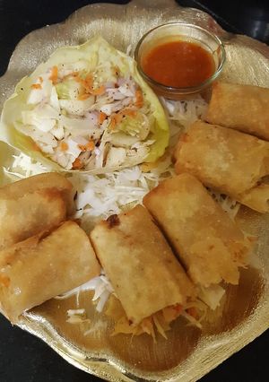 A picture of Spring rolls with kimchi salad and schezwan sauce dip.