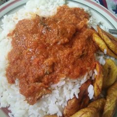 A picture of Rice, stew and fried plantain.