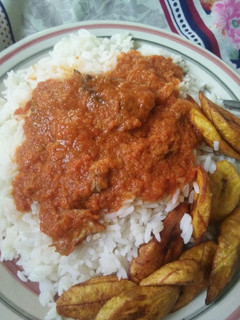 A picture of Rice, stew and fried plantain.