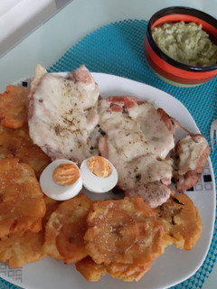 Una foto de Pollo con queso gratinado patacón y ensalada de guacamole