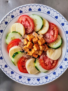 Una foto de Ensalada plato completo de pepino, tomate, mozzarella, tofu al pimentón, enriquecida con gomashio 🥗