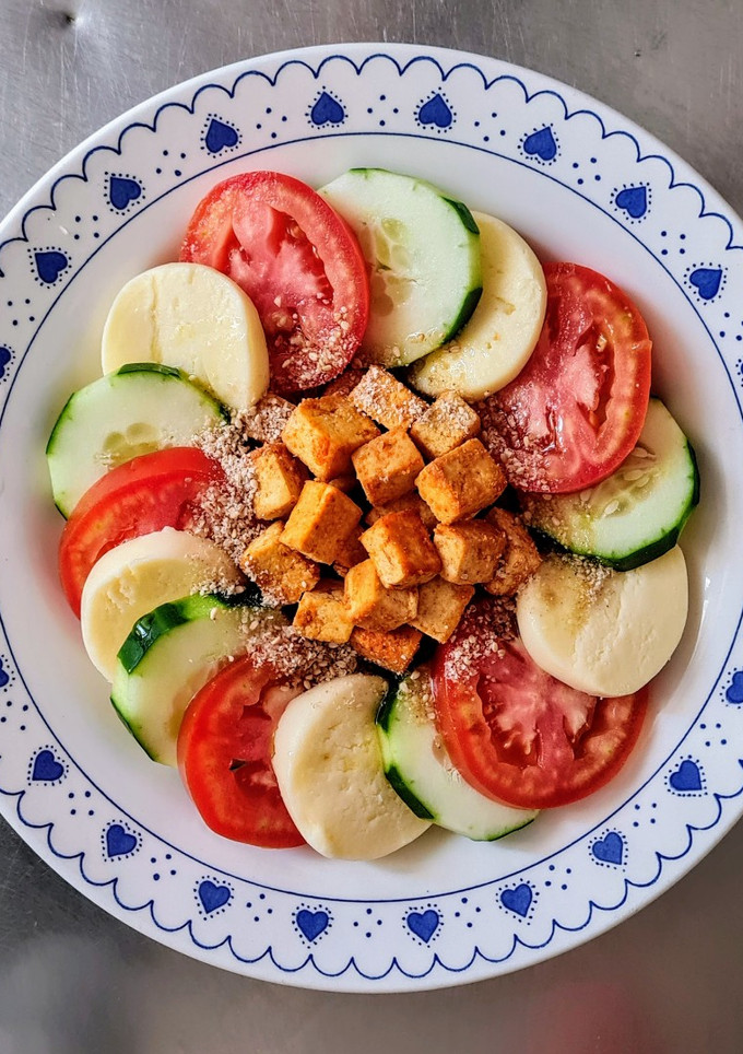 Una foto de Ensalada plato completo de pepino, tomate, mozzarella, tofu al pimentón, enriquecida con gomashio 🥗