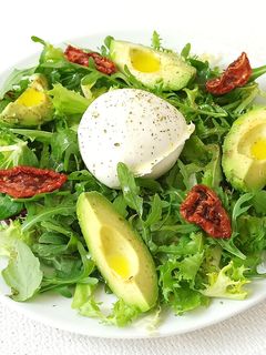 Una foto de Ensalada de rúcula, canónigos, aguacate, tomates secos y queso mozzarella de búfala