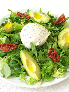 Una foto de Ensalada de rúcula, canónigos, aguacate, tomates secos y queso mozzarella de búfala