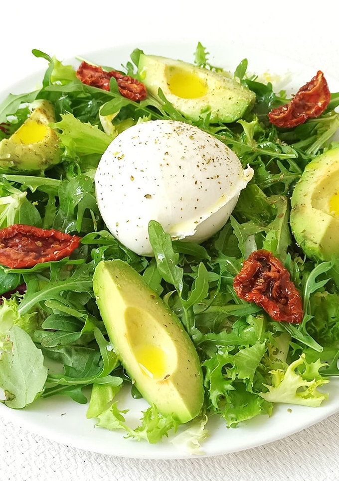 Una foto de Ensalada de rúcula, canónigos, aguacate, tomates secos y queso mozzarella de búfala
