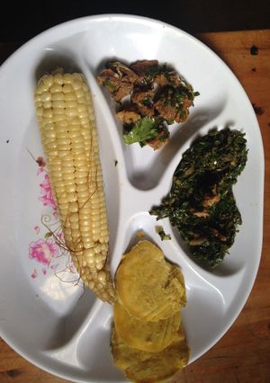 A picture of Boiled maize served with boiled sweet potatoes and fried beef with kales.