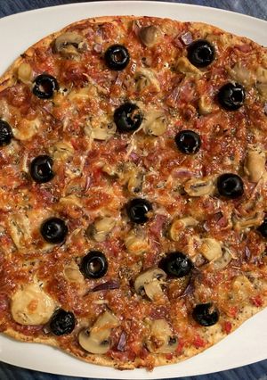 Una foto de Pizza de jamón serrano con aceitunas negras