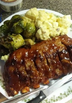 A picture of BBQ pork ribs and no potato, potato salad, Brussel spouts.