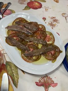 Una foto de Tomates con anchoas, aceite, vinagre y sal