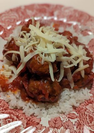 A picture of Beef meatballs in tomato sauce and rice.