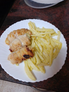 Una foto de Rollitos de pechuga rellenos de jamón serrano, queso y espinacas con papas fritas