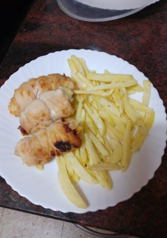 Una foto de Rollitos de pechuga rellenos de jamón serrano, queso y espinacas con papas fritas