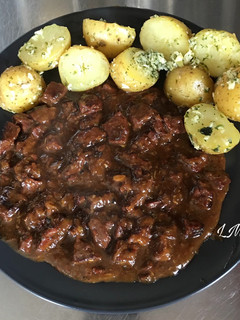 Una foto de Carne estofada con cerveza, acompañada de patatas condimentadas con aceite ajo y perejil