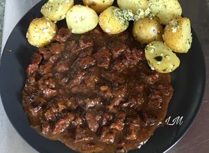 Foto principal de Carne estofada con cerveza, acompañada de patatas condimentadas con aceite ajo y perejil