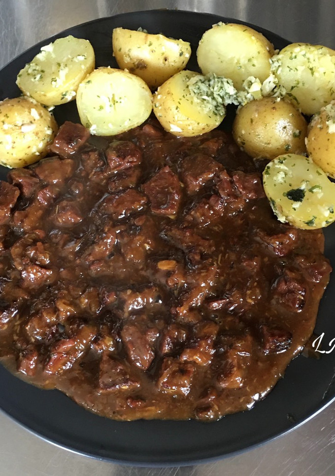 Una foto de Carne estofada con cerveza, acompañada de patatas condimentadas con aceite ajo y perejil