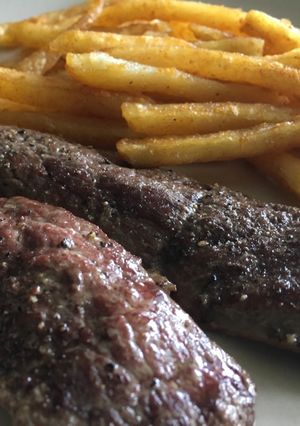 A picture of Deer meat with french fries.