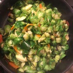 A picture of Fried brussel sprouts with carrots and zucchini.