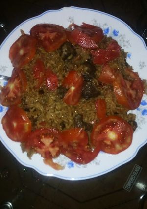 A picture of Beef pilau garnished with tomatoes.